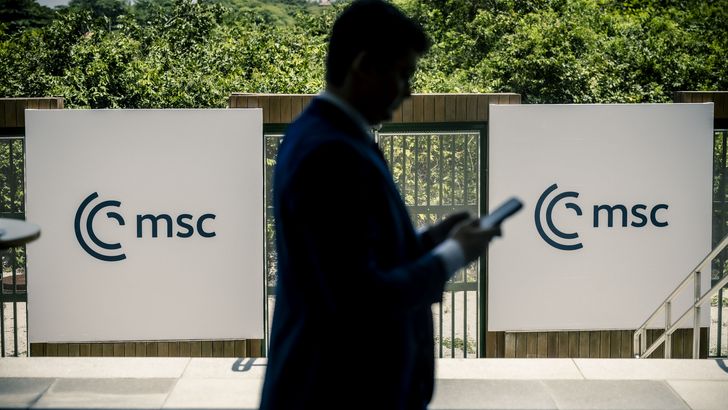 Mann läuft vor MSC-Logo mit Handy in der Hand.